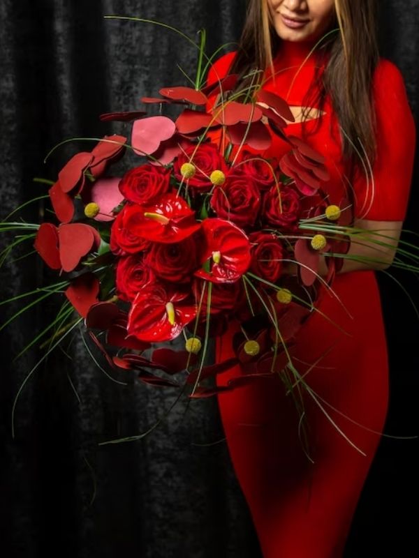 elinde kırmızı antoryum çiçeği olan bir kadın