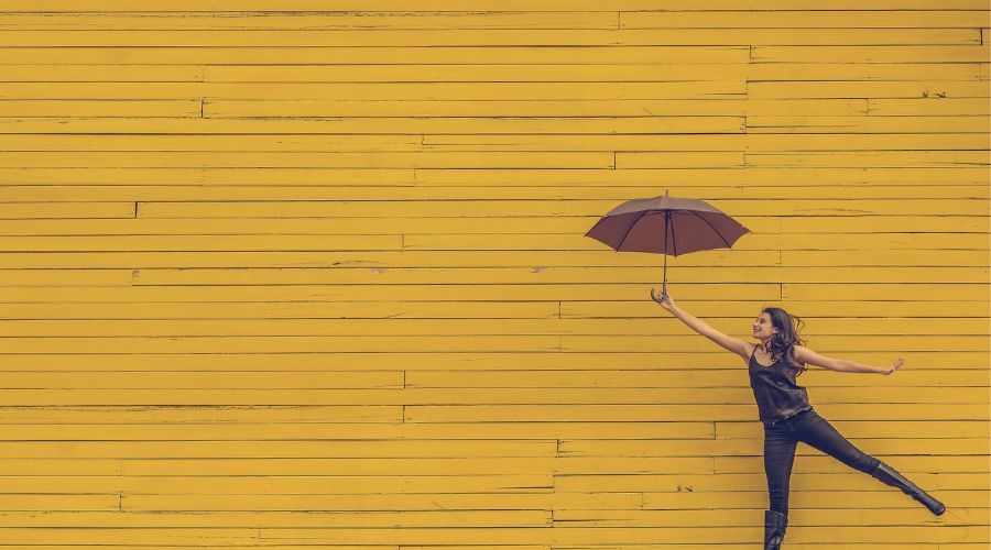 sarı renge boyanmış duvar ve önüne şemsiye ile poz vermiş kadın