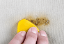 a detailed close-up of a hand effectively removing a stubborn stain from a fabric surface create in horizontal format do not write text on image