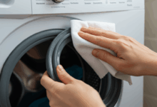 close-up of hands wiping down a washing machine's rubber seal with a disinfectant cloth create in horizontal format do not write text on image