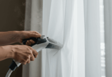 close-up of hands vertically steaming a sheer white curtain to remove wrinkles create in horizontal format do not write text on image