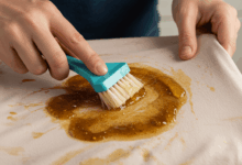 hands applying a stain remover to a piece of clothing with a stubborn curry stain create in horizontal format do not write text on image