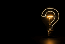 A minimalist image of a single lightbulb illuminating a question mark symbolizing the nature of inquiry and philosophical thought