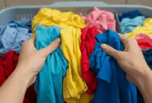hands carefully sorting different colored garments before washing create in horizontal format do not write text on image