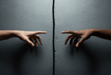 hands reaching out to connect but separated by a wall