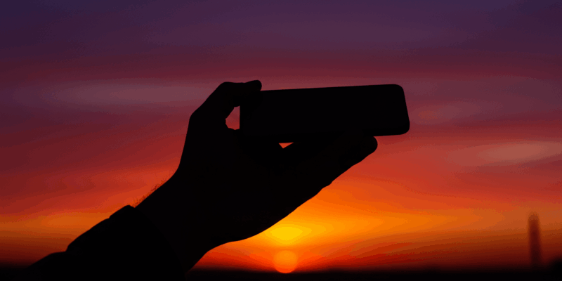 a silhouette of a hand holding a phone
