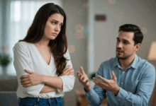 A woman looking away from her partner appearing withdrawn and uninterested while the man attempts to engage her in conversation with a backdrop of a blurred home interior